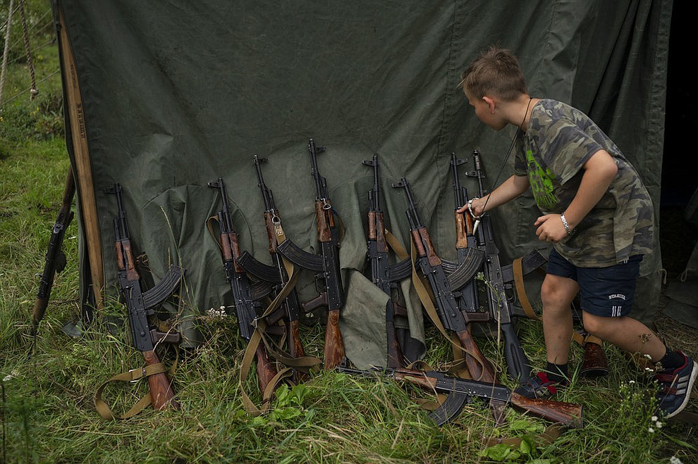 In this July 28, 2018 photo, a young participant of the "Temper of will" summer camp, organized by the nationalist Svoboda party, grabs his AK-47 during a tactical exercise in a village near Ternopil, Ukraine. "We never aim guns at people," instructor Yuri "Chornota" Cherkashin tells campers. "But we don't count separatists, little green men, occupiers from Moscow as people, so we can and should aim at them." (AP Photo/Felipe Dana)