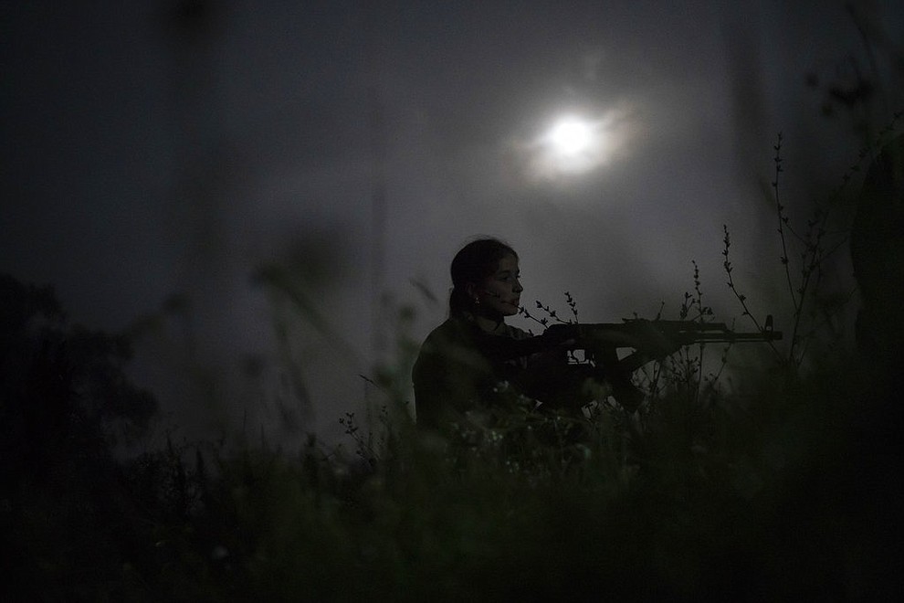 In this July 29, 2018 photo, a young participant of the "Temper of will" summer camp, organized by the nationalist Svoboda party, takes position with her unloaded AK-47 riffle during a night exercise in a village near Ternopil, Ukraine. (AP Photo/Felipe Dana)