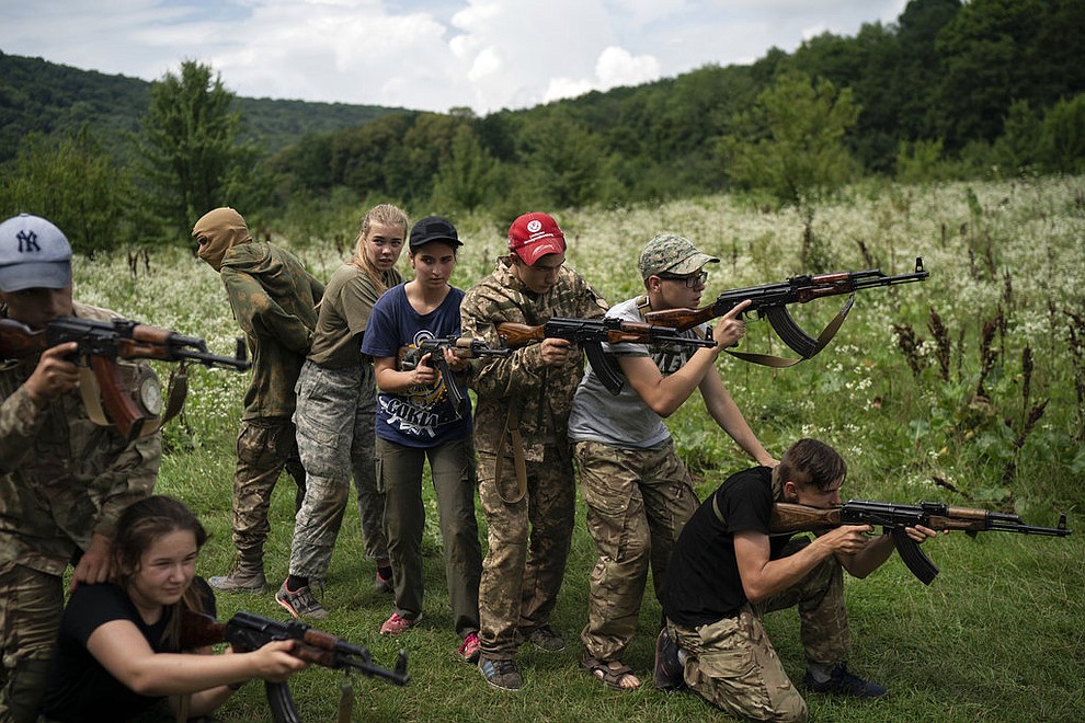In this July 29, 2018 photo, young participants of the "Temper of will" summer camp, organized by the nationalist Svoboda party, practice tactical formations with AK-47 assault riffles in a village near Ternopil, Ukraine. (AP Photo/Felipe Dana)