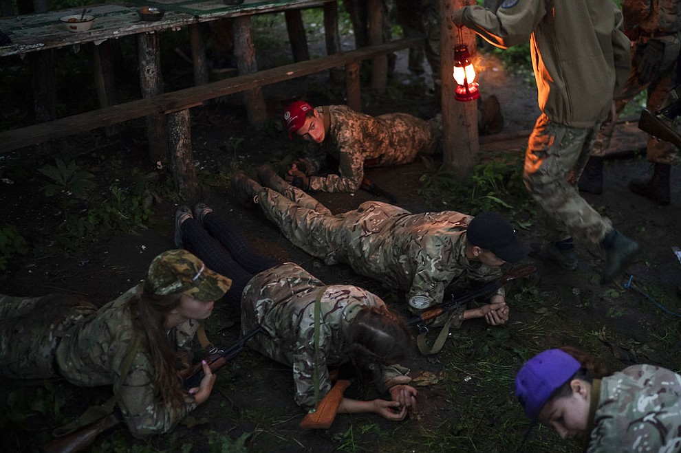 In this July 28, 2018 photo, young participants of the "Temper of will" summer camp, organized by the nationalist Svoboda party, hold a plank position before having dinner in a village near Ternopil, Ukraine. (AP Photo/Felipe Dana)