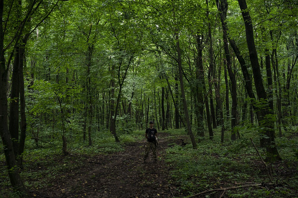 In this July 27, 2018 photo, a member of Sokil (Falcon), the youth wing of the nationalist Svoboda party, stands in a forest as he guides participants to the "Temper of will" summer camp in a village near Ternopil, Ukraine. (AP Photo/Felipe Dana)