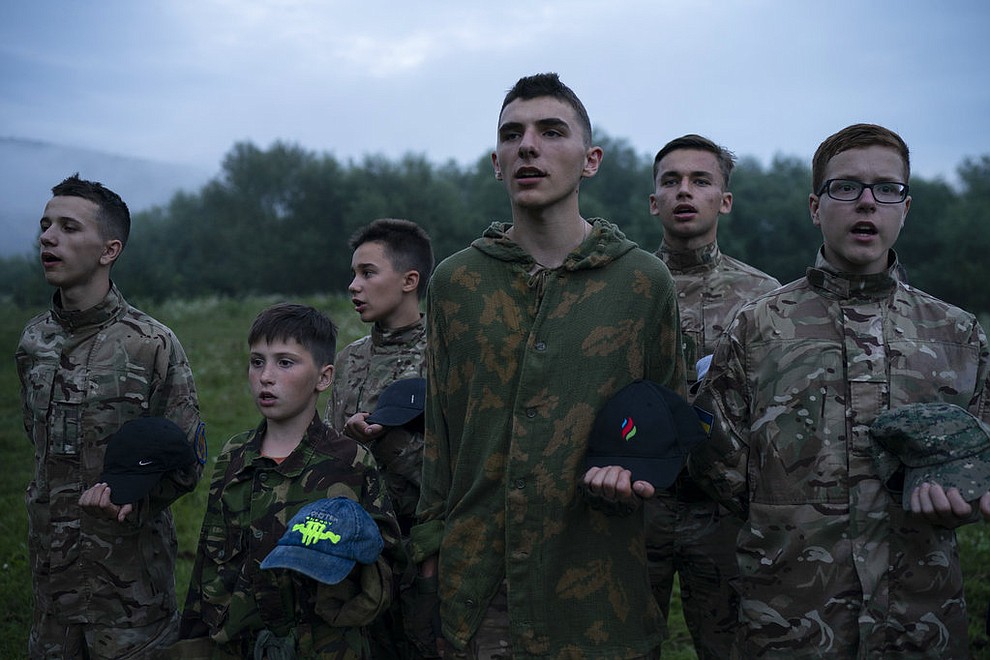 In this July 28, 2018 photo, Mykhailo, 18, center, leads other young participants of the "Temper of will" summer camp, organized by the nationalist Svoboda party, as they stand in formation singing nationalist songs in a village near Ternopil, Ukraine. Mykhailo is the oldest of the campers. "Every moment things can go wrong in our country. And one has to be ready for it," he said. "That's why I came to this camp. To study how to protect myself and my loved ones." (AP Photo/Felipe Dana)