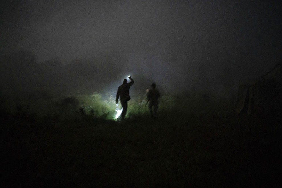 In this July 29, 2018 photo, instructor Georgiy Barylenko, left, holds a flashlight as he walks with a young participant of the "Temper of will" summer camp, organized by the nationalist Svoboda party, during a night drill in a village near Ternopil, Ukraine. (AP Photo/Felipe Dana)