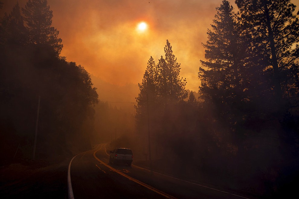 A vehicle drives through smoke from a wildfire near Pulga, Calif., Sunday, Nov. 11, 2018. (AP Photo/Noah Berger)