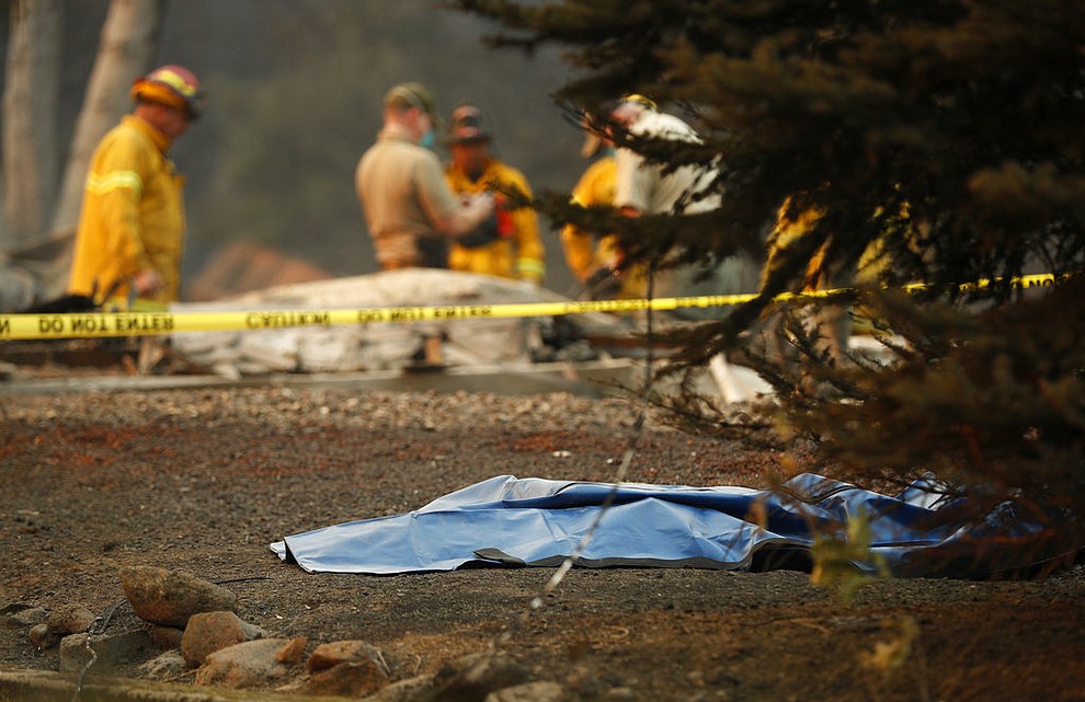 A bag containing human remains lies on the ground as officials continue to search at a burned out home at the Camp Fire, Sunday, Nov. 11, 2018, in Paradise, Calif. (AP Photo/John Locher)