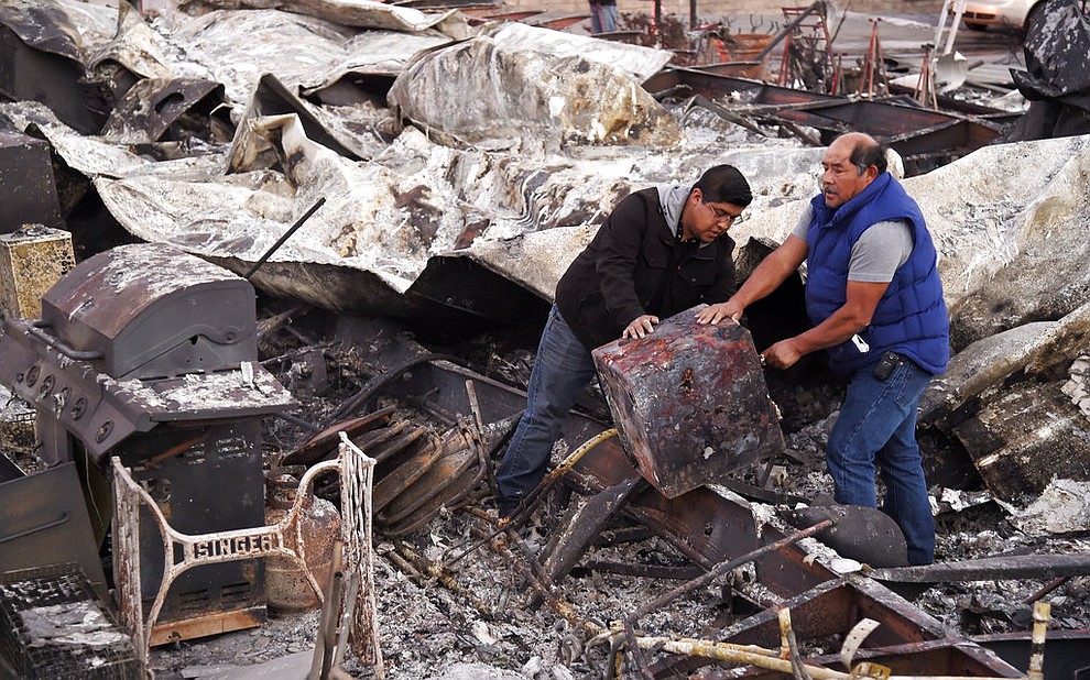 Santos Alvarado, right, and his son Ricky recover a safe deposit box from their destroyed home at Seminole Springs Mobile Home Park, Sunday, Nov. 11, 2018, following devastating wildfires in the area in Agoura Hills, Calif. (AP Photo/Chris Pizzello)