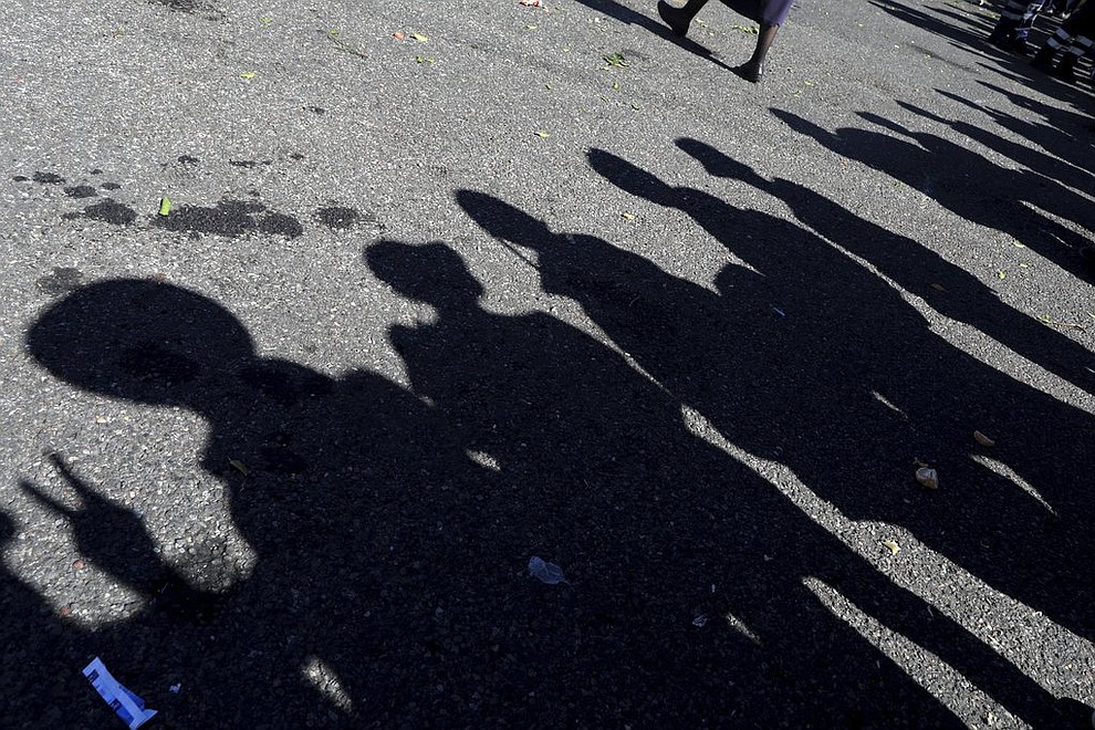 The shadows of Central American migrants, part of the caravan hoping to reach the U.S. border, stand in a line to board buses, on their way to Mazatlan, Mexico, Tuesday, Nov. 13, 2018. The U.S. government said it was starting work Tuesday to "harden" the border crossing from Tijuana, Mexico, to prepare for the arrival of a migrant caravan leapfrogging its way across western Mexico. (AP Photo/Rodrigo Abd)