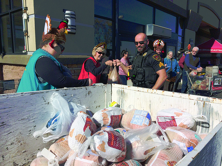 Prescott Valley Police Sgt. Joe McCamish helps load donated turkeys into the Yavapai Food Bank trailer Monday, Nov. 19, during the Prescott Valley Chamber of Commerce Flying High Turkey Drive at the Prescott Valley Fry’s Food and Drug store. In a short period of time, generous donors had dropped off about 40 turkeys and many bags of potatoes and other food items for families in need. (Sue Tone/Tribune)