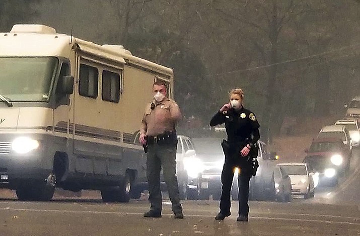 In this Nov. 8, 2018, photo provided by Michael Zuccolillo, Butte County Sheriff Kory Honea and his daughter, Police Officer Kassidy Honea, direct traffic during the evacuation of Paradise, Calif, as the Camp Fire bears down on them. (Michael Zuccolillo via AP)