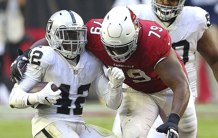 In this Sunday, Nov. 18, 2018, file photo, Oakland Raiders defensive back Karl Joseph (42) is hit by Arizona Cardinals offensive tackle Korey Cunningham (79) after an interception in the first half of an NFL football game in Glendale, Ariz. Add Cunningham to the list of rookies to start for the sputtering Cardinals. The seventh-round draft pick has filled in for injured D.J. Humphries at left tackle the last two weeks and is the new starter at right tackle this week after the team cut Andre Smith. (Ross D. Franklin/AP, File)