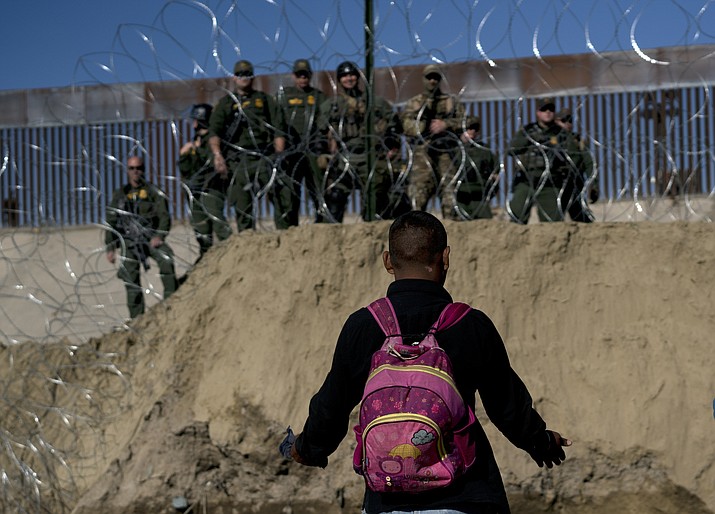 A Honduran migrant converses with U.S border agents on the other side of razor wire after they fired tear gas at migrants pressuring to cross into the U.S. from Tijuana, Mexico, Sunday, Nov. 25, 2018. (AP Photo/Ramon Espinosa)