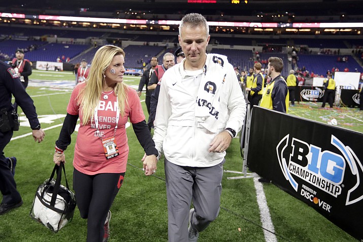Ohio State head coach Urban Meyer walks off the field with his wife, Shelley Meyer, early Sunday, Dec. 2, 2018, after defeating Northwestern in the Big Ten championship NCAA college football game in Indianapolis. Ohio State won 45-24. (AP Photo/Michael Conroy)