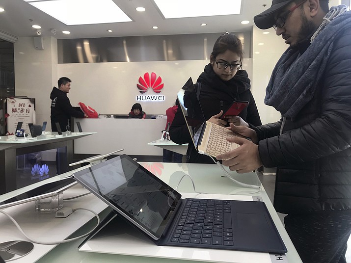 Foreigners look at a Huawei computer at a Huawei store in Beijing, China, Thursday, Dec. 6, 2018. Canadian authorities said Wednesday that they have arrested the chief financial officer of China's Huawei Technologies for possible extradition to the United States. (AP Photo/Ng Han Guan)