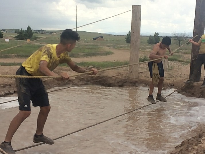 Orlando Santoyo and Fernando Soto, members of the Chino Valley High School boys soccer team, inch along on ropes suspended over a pool of mud at the 2018 Chino Mud Run at Old Home Manor in Chino Valley on Saturday, Aug. 25. (Jason Wheeler/Review file)