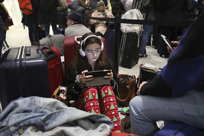 Passengers at Gatwick airport settle down to wait for their flights following the delays and cancellations brought on by drone sightings near the airfield, in London, Friday Dec. 21, 2018. New drone sightings Friday caused fresh chaos for holiday travelers at London's Gatwick Airport. (John Stillwell/PA via AP)