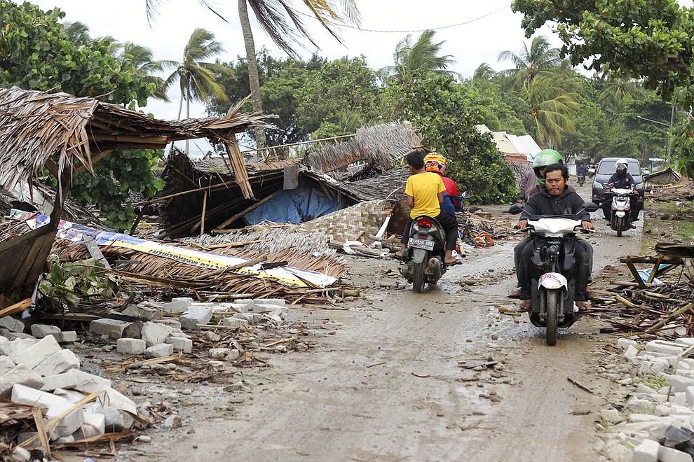 Motorists ride past houses damaged by a tsunami, in Carita, Indonesia, Sunday, Dec. 23, 2018. The tsunami apparently caused by the eruption of an island volcano killed a number of people around Indonesia's Sunda Strait, sending a wall of water crashing some 65 feet (20 meters) inland and sweeping away hundreds of houses including hotels, the government and witnesses said. (AP Photo)