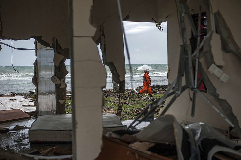 A rescuer is seen through a damaged house as he takes part in a search operation of tsunami victims in Carita, Indonesia, Sunday, Dec. 23, 2018. The tsunami occurred after the eruption of a volcano around Indonesia's Sunda Strait during a busy holiday weekend, sending water crashing ashore and sweeping away hotels, hundreds of houses and people attending a beach concert. (AP Photo/Fauzy Chaniago)