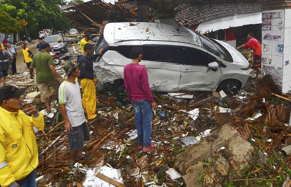 People inspect the wreckage of a car swept away by a tsunami in Carita, Indonesia, Sunday, Dec. 23, 2018. The tsunami occurred after the eruption of a volcano around Indonesia's Sunda Strait during a busy holiday weekend, sending water crashing ashore and sweeping away hotels, hundreds of houses and people attending a beach concert. (AP Photo)