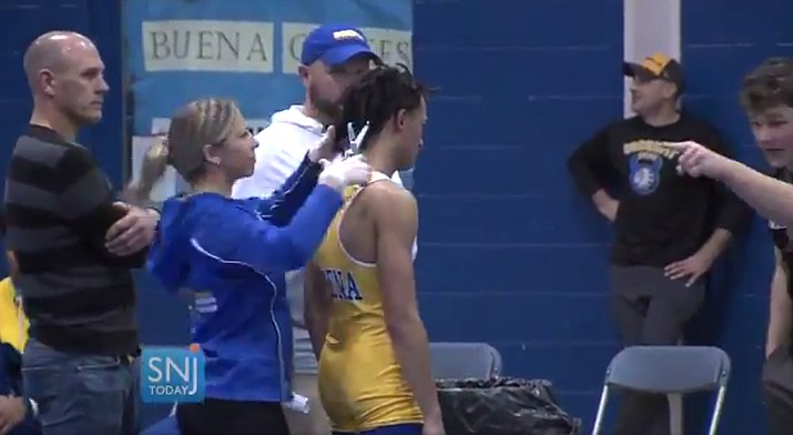 In this image taken from a Wednesday, Dec. 19, 2018 video provided by SNJTODAY.COM, Buena Regional High School wrestler Andrew Johnson gets his hair cut courtside minutes before his match in Buena, N.J., after a referee told Johnson he would forfeit his bout if he didn’t have his dreadlocks cut off. (Michael Frankel/SNJTODAY.COM viavAP)