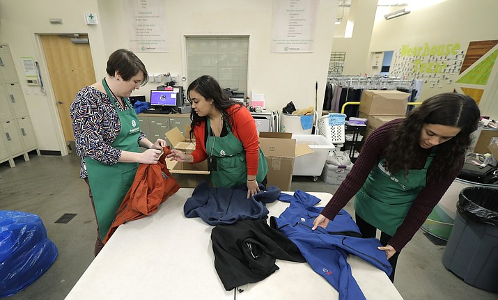 In this Friday, Dec. 21, 2018, photo, from left, Rebecca Schaechter, Nicole Herron and Rachel Herron fold and sort donated clothes at Treehouse, a nonprofit organization in Seattle that serves the needs of children in the foster-care system. The charity was one of several that received donations from the $11 million secret estate of Alan Naiman -- a social worker who died from cancer earlier in 2018 after living a private life of frugality and concern for children facing hardship. (AP Photo/Ted S. Warren)