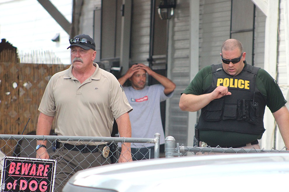July 17 – Jeremiah Grant Peacey, background, watches authorities leave his property July 17. Peacey has been accused of taking a suitcase containing about $170,000. In June, a Valle Vista woman reported leaving the cash-filled suitcase on the bottom of a shopping cart at Walmart. (Photo by Beau Bearden/Daily Miner)