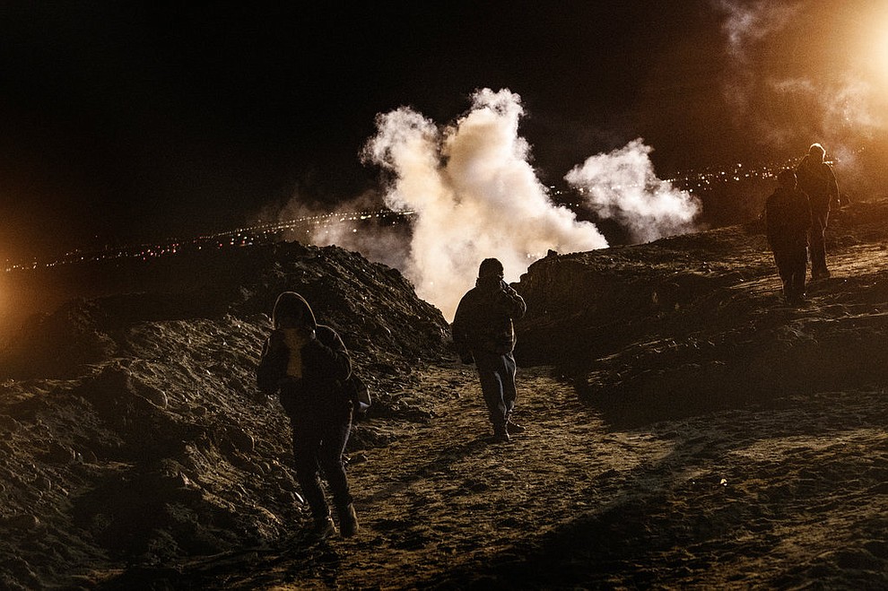 Migrants run as tear gas is thrown by U.S. Border Protection officers to the Mexican side of the border fence after they climbed the fence to get to San Diego, Calif., from Tijuana, Mexico, Tuesday, Jan. 1, 2019. Discouraged by the long wait to apply for asylum through official ports of entry, many migrants from recent caravans are choosing to cross the U.S. border wall and hand themselves in to border patrol agents. (AP Photo/Daniel Ochoa de Olza)