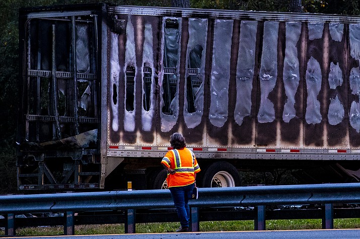 A worker looks at a charred semi-truck after a wreck with multiple fatalities on Interstate 75, south of Alachua, near Gainesville, Fa., Thursday, Jan. 3, 2019. Two big rigs and two passenger vehicles collided and spilled diesel fuel across the Florida highway Thursday, sparking a massive fire that killed several people, authorities said. (Lauren Bacho/The Gainesville Sun via AP)