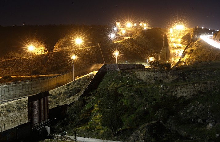 Floodlights from the U.S, illuminate multiple border walls Monday, Jan. 7, 2019, seen from Tijuana, Mexico. With no breakthrough in sight, President Donald Trump will argue his case to the nation Tuesday night that a "crisis" at the U.S.-Mexico border requires the long and invulnerable wall he's demanding before ending the partial government shutdown. (AP Photo/Gregory Bull)