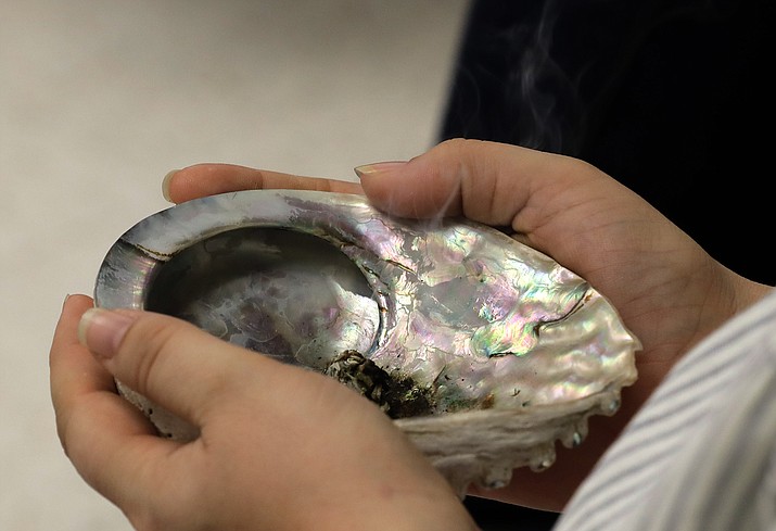 A participant in a talking circle meeting at the Urban Indian Health Institute in Seattle an abalone shell with burning sage in it, Friday, Jan. 11, during a discussion of the practice of traditional Indian medicine, including blessings and smudging.  (Ted S. Warren/AP)