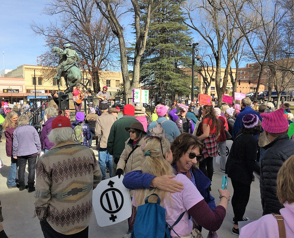Anne Nightingale, 61, left front, and Bonnie Norvaisis, 66, embrace during the Yavapai County Women March On event at the Yavapai County Courthouse Jan. 19, 2019, as musicians sing, "We are like flowers out of concrete; We are like warriors into these streets." (Sue Tone/Courier)