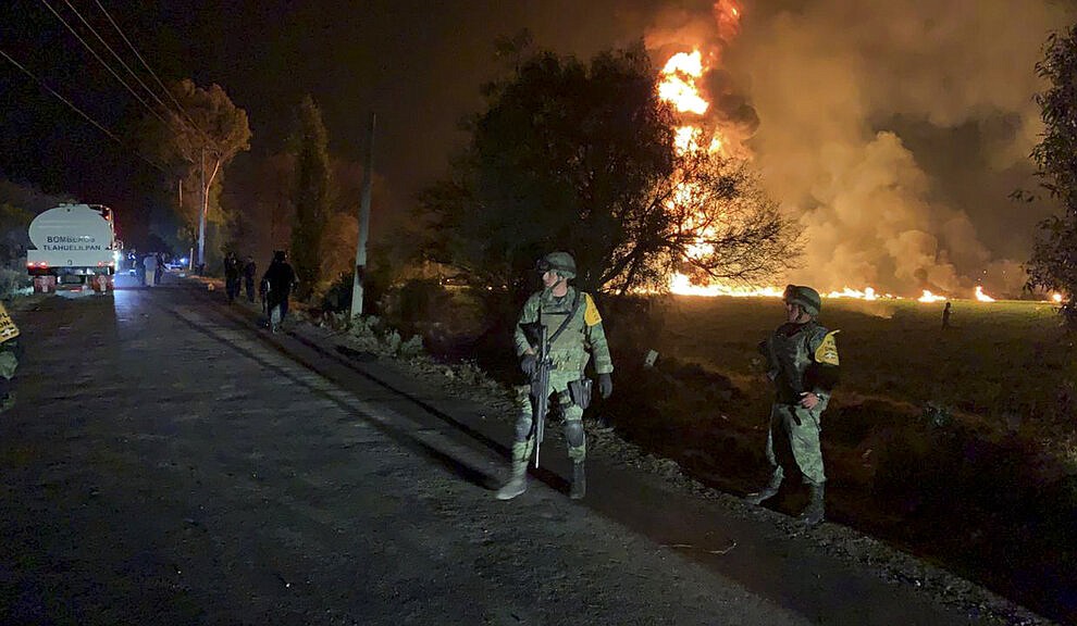 In this image provided by the Secretary of National Defense, soldiers guard in the area near an oil pipeline explosion in Tlahuelilpan, Hidalgo state, Mexico, Friday, Jan. 18, 2019. A huge fire exploded at a pipeline leaking fuel in central Mexico on Friday, killing at least 21 people and badly burning 71 others as locals were collecting the spilling gasoline in buckets and garbage cans, officials said. Officials said the leak was caused by an illegal tap that fuel thieves had drilled into the pipeline in a small town in the state of Hidalgo, about 62 miles (100 kilometers) north of Mexico City. (Secretary of National Defense via AP)