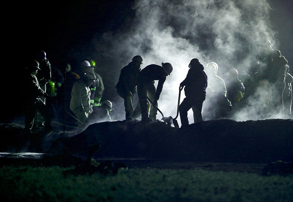 Staff of Pemex, Petroleos Mexicanos, works the area of a oil pipeline explosion in Tlahuelilpan, Hidalgo state, Mexico, Saturday, Jan. 19, 2019. A massive fireball that engulfed people scooping up fuel spilling from a pipeline ruptured by thieves in central Mexico killed several people and badly burned others. (AP Photo/Claudio Cruz)