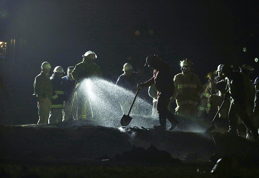 Staff of Pemex, Petroleos Mexicanos, works the area of a oil pipeline explosion in Tlahuelilpan, Hidalgo state, Mexico, Saturday, Jan. 19, 2019. A massive fireball that engulfed people scooping up fuel spilling from a pipeline ruptured by thieves in central Mexico killed several people and badly burned others. (AP Photo/Claudio Cruz)