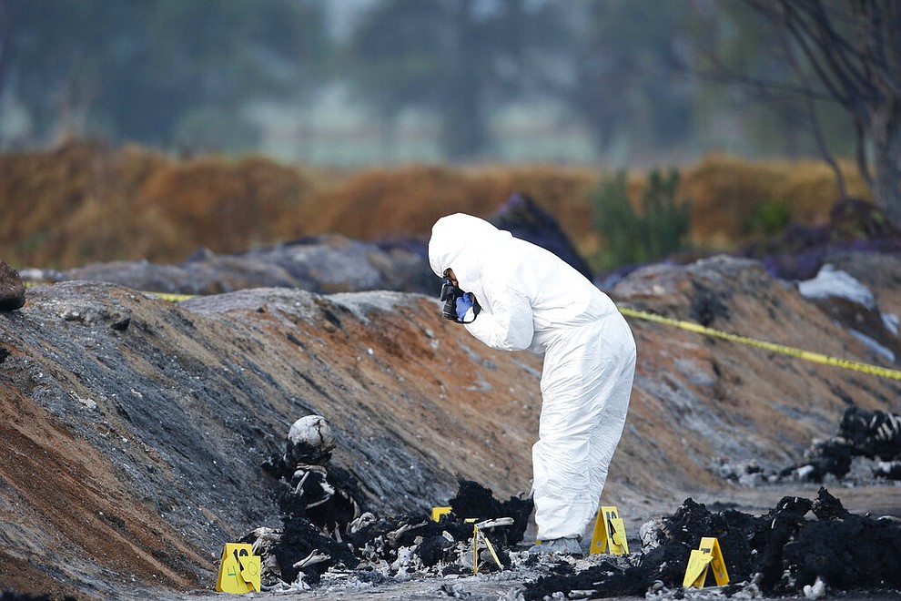 EDS NOTE: GRAPHIC CONTENT - A forensic experts take picture burned body in the area an oil pipeline explosion in Tlahuelilpan, Hidalgo state, Mexico, Saturday, Jan. 19, 2019. A massive fireball that engulfed people scooping up fuel spilling from a pipeline ruptured by thieves in central Mexico killed dozens of people and badly burned many more. (AP Photo/Claudio Cruz)