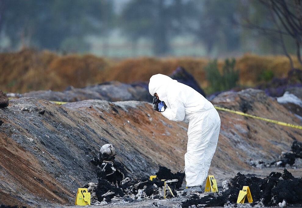 EDS NOTE: GRAPHIC CONTENT - A forensic experts take picture burned body in the area an oil pipeline explosion in Tlahuelilpan, Hidalgo state, Mexico, Saturday, Jan. 19, 2019. A massive fireball that engulfed people scooping up fuel spilling from a pipeline ruptured by thieves in central Mexico killed dozens of people and badly burned many more. (AP Photo/Claudio Cruz)