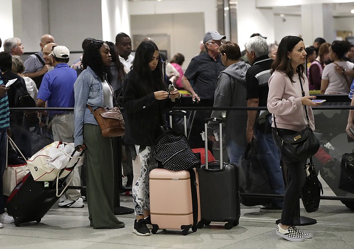 Passengers wait in line at a security checkpoint at Miami International Airport in Miami. While security screeners and air traffic controllers have been told to keep working, FAA safety inspectors weren’t working until the agency began recalling some Jan. 12. (AP Photo/Lynne Sladky, File)