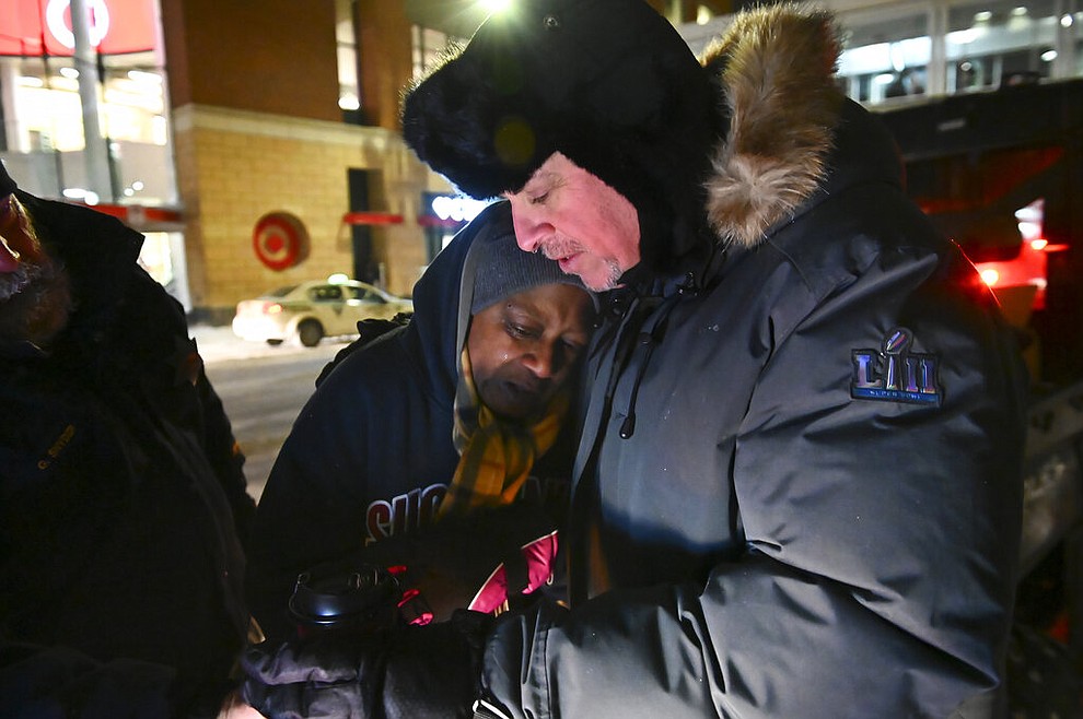 Pastor John Steger, with Grace In The City church, embraces Jearline Cyrus, a homeless woman, in downtown Minneapolis, Tuesday, Jan. 29, 2019, while delivering cold-weather gear, hot chocolate and food with Minneapolis Police Sgt. Grant Snyder. Snyder will be hitting the streets Tuesday and Wednesday night during the height of the big chill to check on the welfare of homeless people who haven't made it into a shelter. (Aaron Lavinsky/Star Tribune via AP)