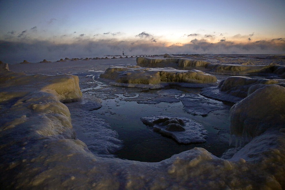 Ice forms along the shore of Lake Michigan before sunrise, Wednesday, Jan. 30, 2019, in Chicago. A deadly arctic deep freeze enveloped the Midwest with record-breaking temperatures on Wednesday, triggering widespread closures of schools and businesses, and prompting the U.S. Postal Service to take the rare step of suspending mail delivery to a wide swath of the region. (AP Photo/Kiichiro Sato)