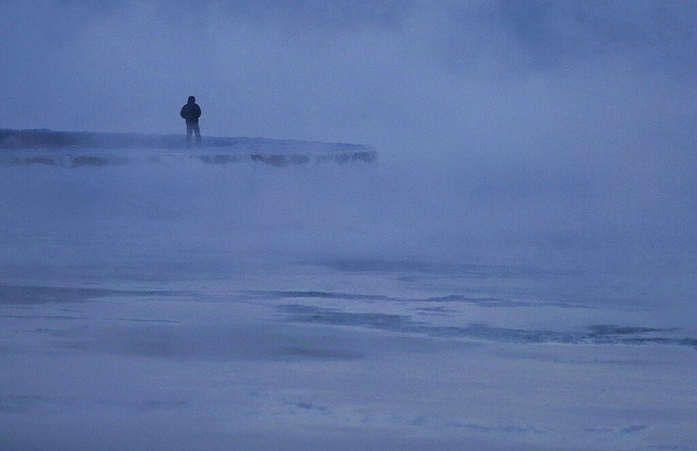 A man walks along the shore of Lake Michigan, Wednesday, Jan. 30, 2019, in Chicago. A deadly arctic deep freeze enveloped the Midwest with record-breaking temperatures on Wednesday, triggering widespread closures of schools and businesses, and prompting the U.S. Postal Service to take the rare step of suspending mail delivery to a wide swath of the region. (AP Photo/Kiichiro Sato)