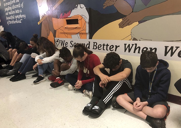 Students at Seminole Middle School in Plantation, Fla., participate in a moment of silence Thursday, Feb. 14, 2019, for the 14 students and three staff members killed one year ago at nearby Marjory Stoneman Douglas High School. They are sitting in front of a new mural depicting musicians from throughout the world that was dedicated to the shooting victims. (Terry Spencer/AP)