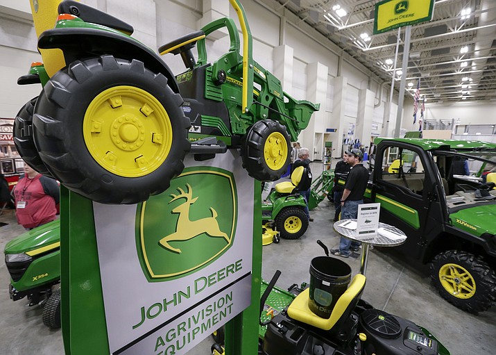 John Deere products, including a toy tractor on the sign, are on display at the "Spring into Spring" home and garden trade show in Council Bluffs, Iowa. Deere cited rising costs and anxious farmers in reporting a profit shortfall for the first quarter Friday, Feb. 15, 2019. (Nati Harnik/AP, File)