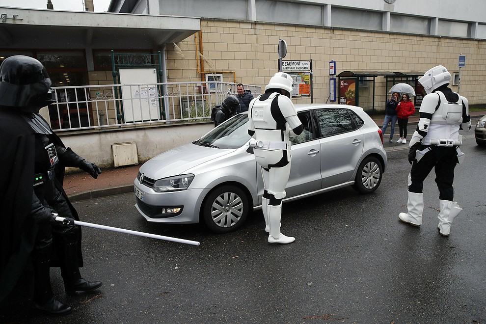 In this Sunday, Feb. 10, 2019, photo, men dressed up as Stormtroopers joke as they approach a vehicle during a national lightsaber tournament in Beaumont-sur-Oise, north of Paris. In France, it is easier than ever now to act out "Star Wars" fantasies. The fencing federation has officially recognized lightsaber dueling as a competitive sport. (AP Photo/Christophe Ena)