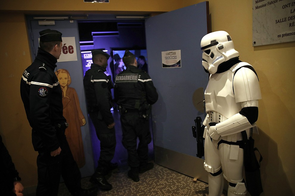 In this Sunday, Feb. 10, 2019, photo, a man dressed up as Stormtrooper and French gendarmes watch a national lightsaber tournament in Beaumont-sur-Oise, north of Paris. (AP Photo/Christophe Ena)