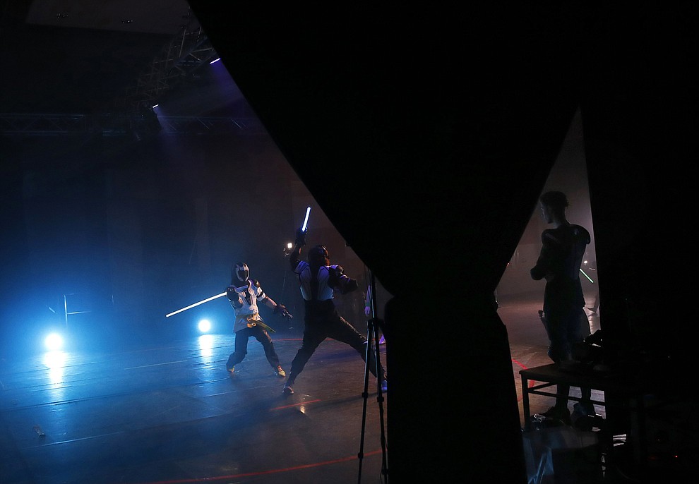 In this Sunday, Feb. 10, 2019, photo, a man watches competitors as they battle during a national lightsaber tournament in Beaumont-sur-Oise, north of Paris. "We wanted it to be safe, we wanted it to be umpired and, most of all, we wanted it to produce something visual that looks like the movies, because that is what people expect," said Michel Ortiz, the tournament organizer. (AP Photo/Christophe Ena)