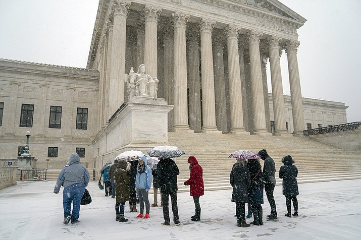 Visitors wait to enter the Supreme Court as a winter snow storm hits the nation's capital making roads perilous and closing most Federal offices and all major public school districts, on Capitol Hill in Washington, Wednesday, Feb. 20, 2019. (AP Photo/J. Scott Applewhite)