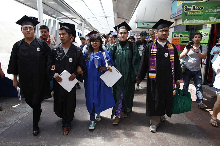 In this July 22, 2013 file photo, “Dreamers” wearing their school graduation caps and gowns to show their desire to finish school in the U.S., march with linked arms to the U.S. port of entry where they planned to request humanitarian parole in Nogales, Mexico. Nine activists in federal custody in Arizona for more than a week after attempting to cross the border from Mexico into the U.S. in protest of American immigration policy have been denied requests to remain in the country on humanitarian grounds, organizers said Thursday, Aug. 1, 2013. The group, referring to themselves as the Dream9, is trying to call attention to hundreds of thousands who have been deported during President Barack Obama’s time in the White House. (Samantha Sais/AP, File)