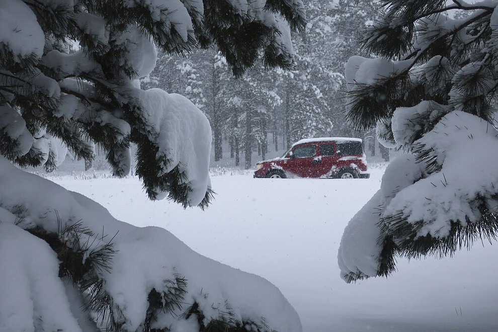 A car drives down Route 66 in Flagstaff, Arizona, on Thursday, Feb. 21, 2019. Schools across northern Arizona canceled classes and some government offices decided to close amid a winter storm that's expected to dump heavy snow in the region. (AP Photo/Felicia Fonseca)