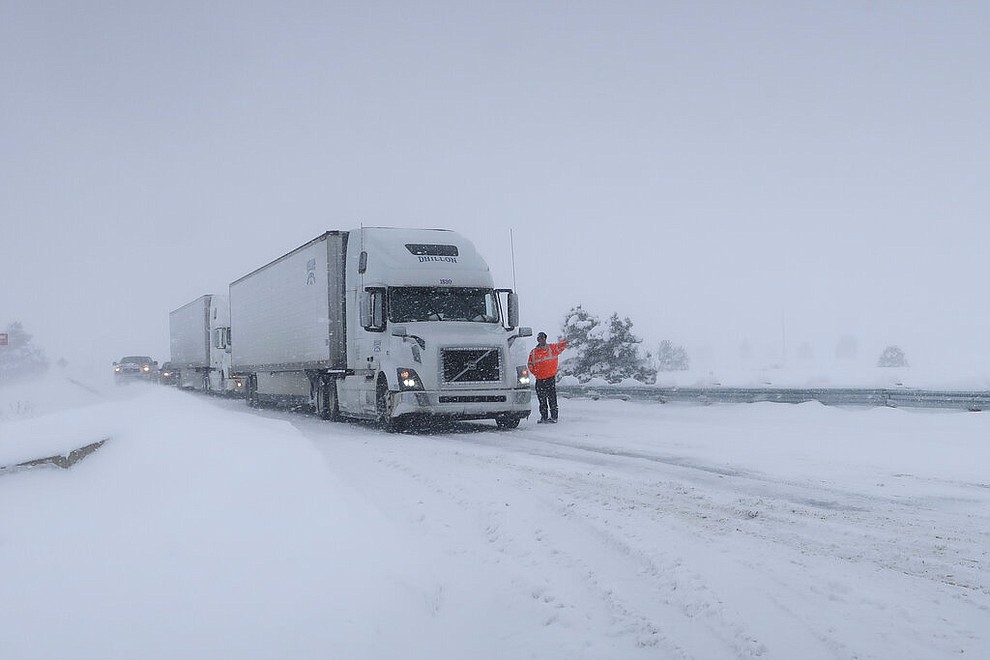 Frank Van Buren, the manager of a travel center, gives direction to semi-truck drivers who are pulling off Interstate 40 in Bellemont, Arizona, on Thursday, Feb. 21, 2019. Feb. 21, 2019. Schools across northern Arizona canceled classes and some government offices decided to close amid a winter storm that's expected to dump heavy snow in the region. (AP Photo/Felicia Fonseca)