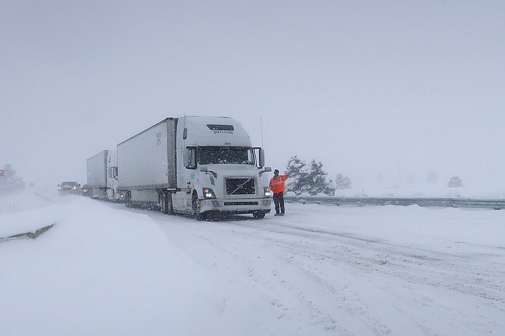 Frank Van Buren, the manager of a travel center, gives direction to semi-truck drivers who are pulling off Interstate 40 in Bellemont, Arizona, on Thursday, Feb. 21, 2019. Feb. 21, 2019. Schools across northern Arizona canceled classes and some government offices decided to close amid a winter storm that's expected to dump heavy snow in the region. (AP Photo/Felicia Fonseca)