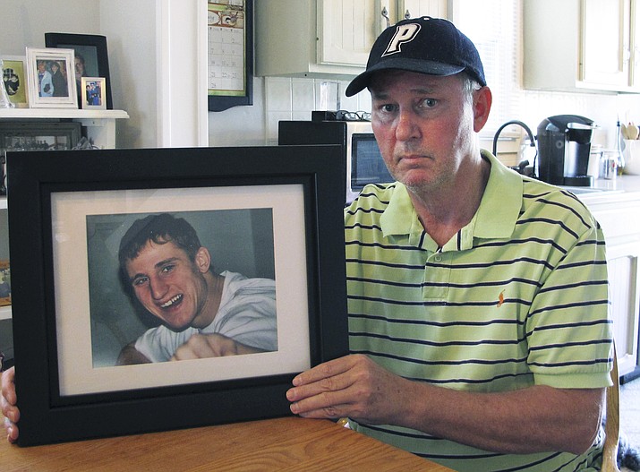 In this Feb. 14, 2019 photo, Dean Palozej poses with a photo of his son, Spencer, in Stafford, Conn. Spencer Palozej died of a fentanyl overdose in last year. His father supports a proposed state law that would create a new murder charge for people who supply drugs that cause fatal overdoses. The opioid crisis has spurred many state and federal officials to consider more serious charges for overdose deaths. (AP Photo/Dave Collins)